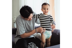 Image A father putting on his sons diaper.